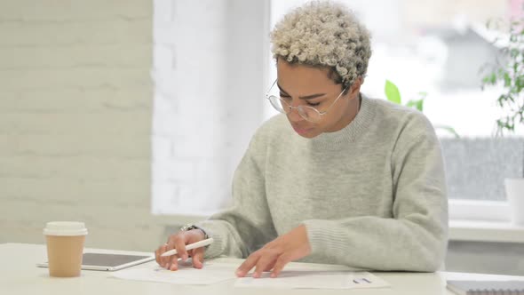 African Woman Writing on Paper in Office