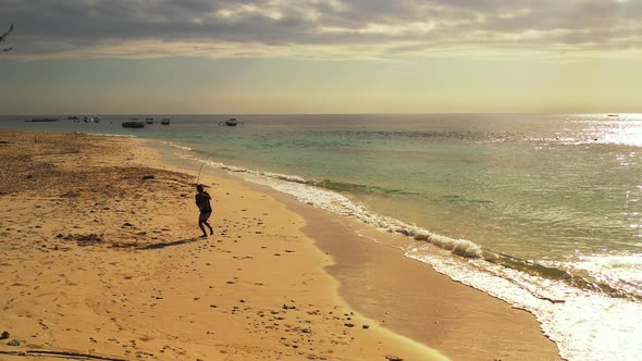 Angling for cute guy on holiday enjoying activities at beach on summer white sandy and blue backgrou