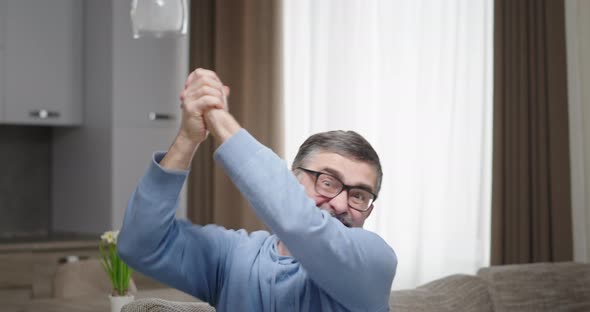 Middle Aged Fan Celebrating Victory on Sofa