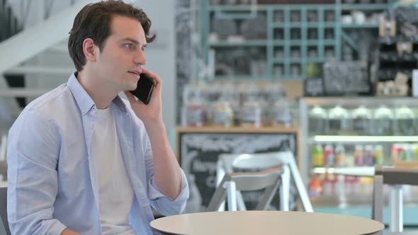 Creative Man Talking on Smartphone in Cafe