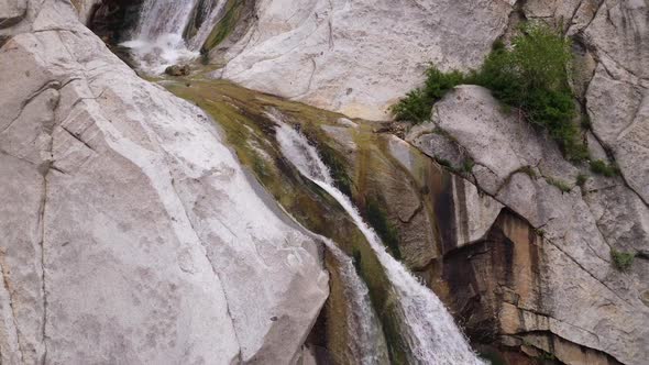 Rising view of waterfall flowing down rock wall