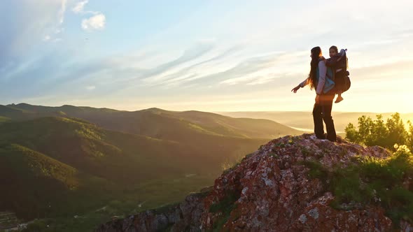 Drone Shot of a Young Mother with Her Young Son in a Carrier Hiking on a Mountain Trail at Sunset