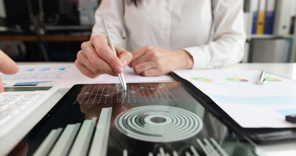 Businesswoman Takes Notes in a Tablet on Statistical Charts Closeup