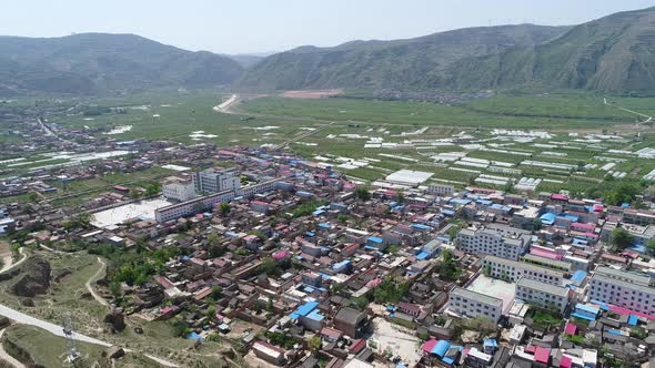 Aerial View of Small Poor Town Next the Arid Terraced Farm Firld Mountain