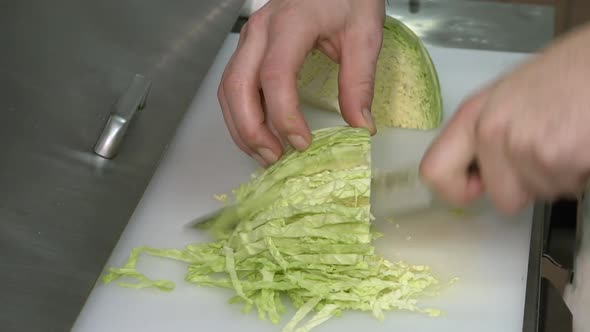 Chef slices and dices cabbage for coleslaw. We have medium and close ups. The shooting style is raw