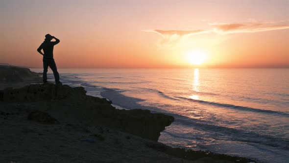 Silhouette of Young Man in Hat Looking at Sunrise in Ocean Coast Beach in New Zealand Summer Nature