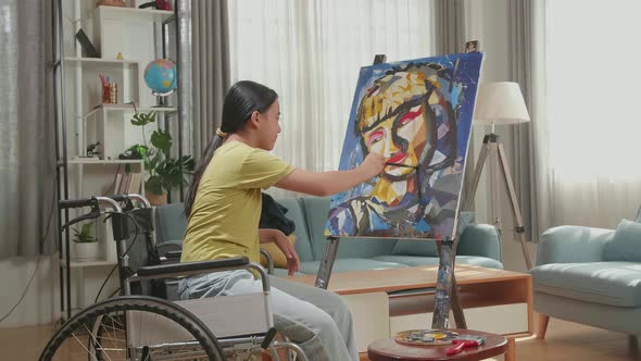 Side View An Asian Artist Girl In Wheelchair Holding Paintbrush Turn To Cross His Arms And Smile