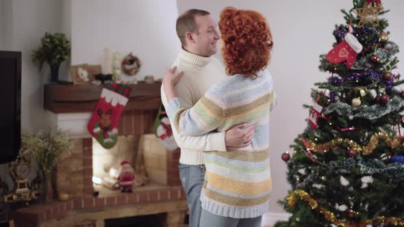 Middle Shot of Happy Caucasian Man and Woman Dancing on New Year at Home Talking and Smiling