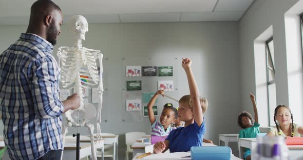 Video of happy african american teacher with class of diverse pupils during anatomy lesson