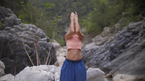 Yoga By Water Stream  a Woman Loose Pants Doing Meditative Exercises