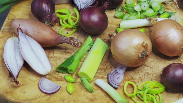 Different types of onion on wooden table. Onions, shallots, red and spring onions variety.