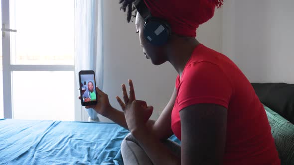 Young woman sitting on bed during video call via smartphone