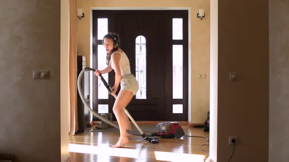 girl with pigtails in headphones vacuuming in the hallway of a house