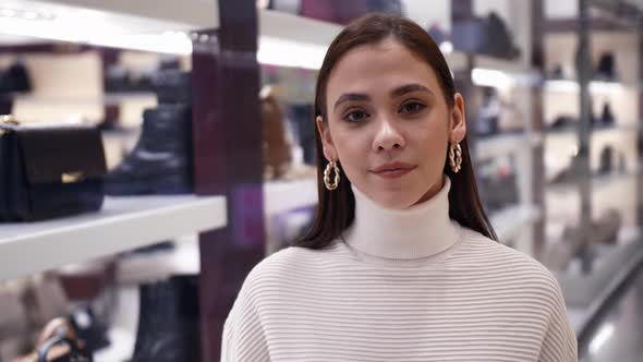 The Girl Chooses Shoes and Bags in the Shopping Center