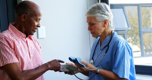 Doctor explaining about blood pressure monitor to senior man 4k