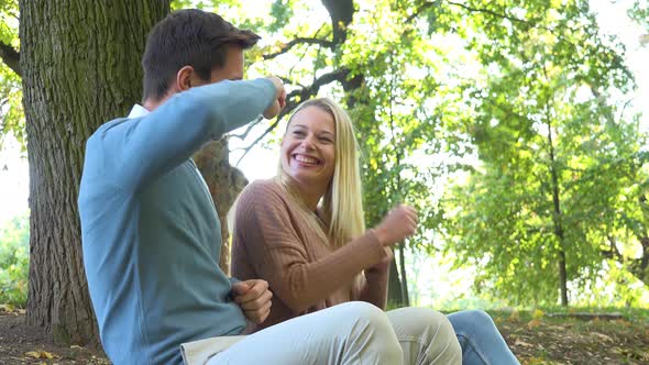 A Man and a Woman Sit in a Park on a Sunny Day and Dance