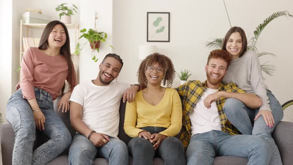 Group Portrait of Smiling Diverse Young People Sitting on Sofa Looking at Camera