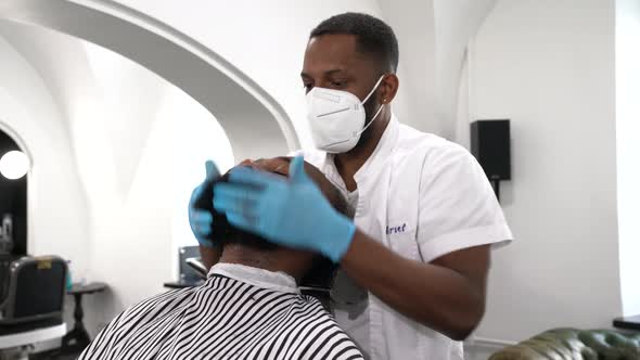 Barber massaging beard of customer