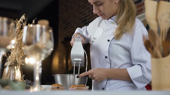 Female Confectioner Mixing white Egg Cream in Bowl Using Motor Mixer