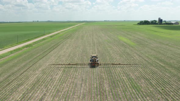 Aerial, tractor spraying pesticides on crops in rural agricultural farm field. Series