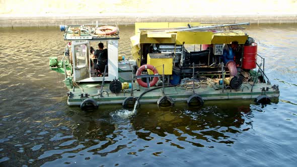 a Small Technical Vessel Sails Through the Water Clearing the Canal of Pollution a Large Motor is