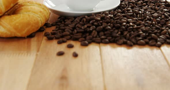 Coffee with roasted coffee beans and croissant