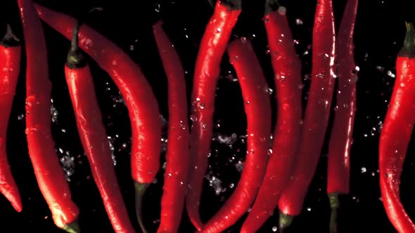 Super Slow Motion Pods of Red Chilli Pepper Rise Up with Splashes of Water