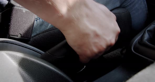 The Hand a Driver Man Controls In and Off Handbrake in a Car. Close Up