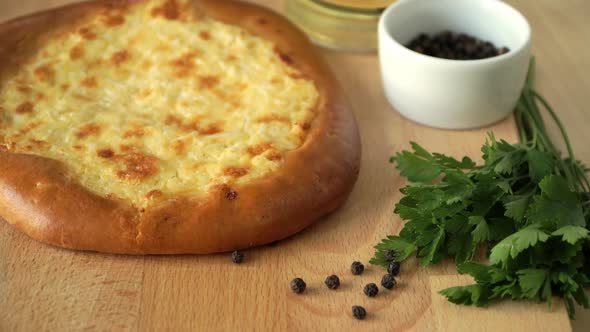 Round Cake with Cheese and Garlic Rotates on Wooden Tray with Olive Oil Parsley Peppercorns