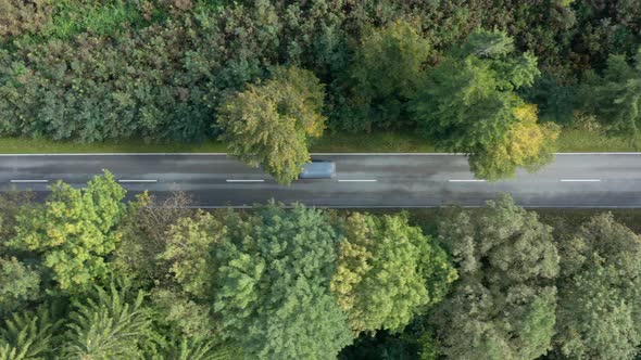 Fast driving blue lorry filmed from above, flying with a drone over the street in the autumnal seaso