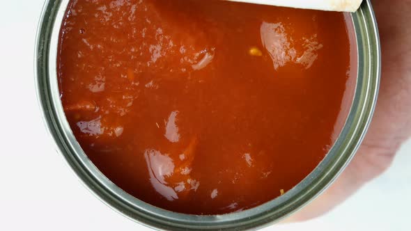 Hand Opens Metallic Tin Can of Tomatoes in Their Own Juice or Tomato Sauce