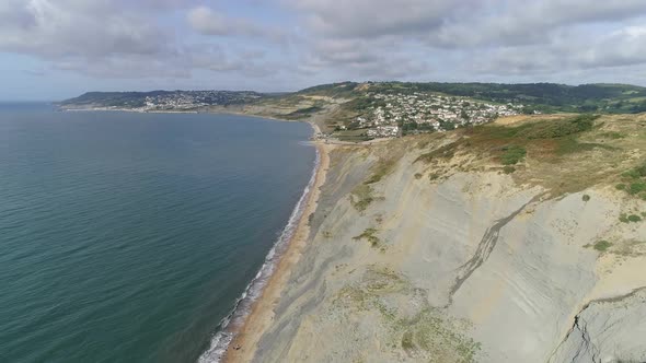 Aerial tracking above the Jurassic coast toward the village of Charmouth, Dorset. Cliffs, sea and th