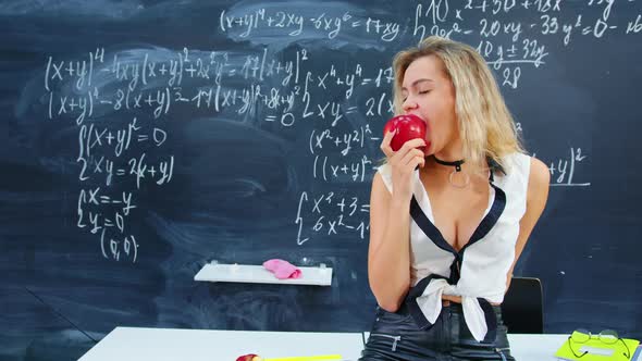 A Hot Teacher Bites an Apple in the Classroom