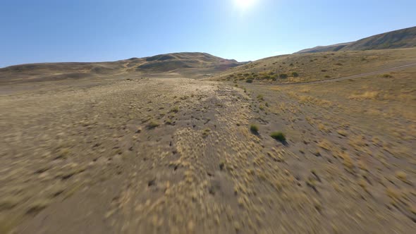 FPV Sports Drone Shot Sunny Panorama Hilly Desert Terrain Yellow Dry Structure Sun Light Blue Sky