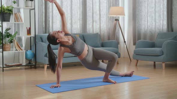 Young Asian Athletic Female Exercising, Stretching And Practicing Yoga At Home