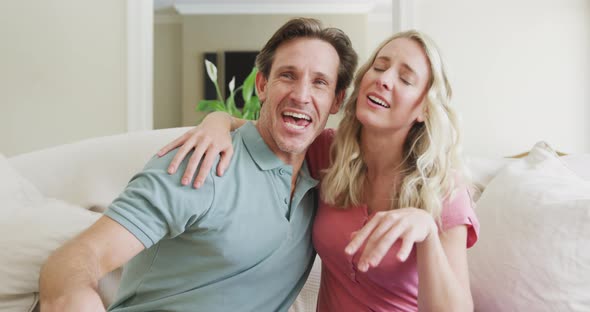 Portrait of happy caucasian couple looking at camera in living room