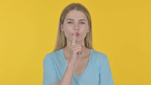 Young Woman with Finger on Lips, Silence Yellow Screen