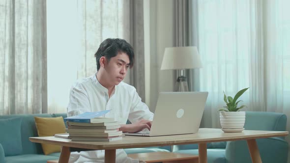 Asian Man Student Using Computer To Study Online At Home