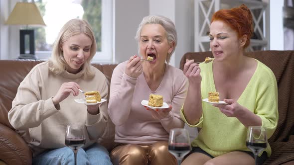 Front View Portrait of Three Happy Adult Caucasian Slim Women Tasting Delicious Cake Smiling Talking