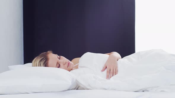 Young woman lying in the bed. Beautiful blond sleeping girl. Morning in the bedroom.