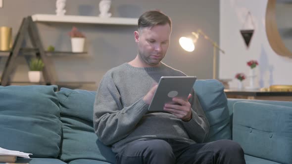 Casual Manusing Tablet While Sitting on Sofa