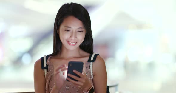 Woman use of mobile phone with shopping center background