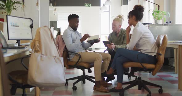 Happy diverse business people discussing with documents in creative office