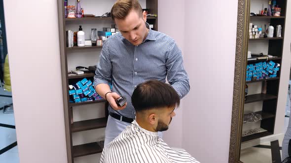 A Skilled Miller Does His Job. With the Hair Clipper He Does a Young Man's Hairstyle.