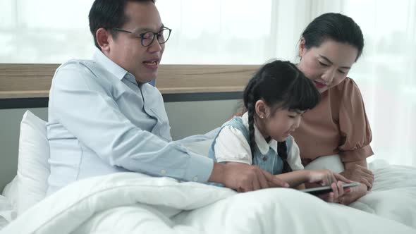 Father and mother are teaching their daughter homework at home, cosy family and education concept