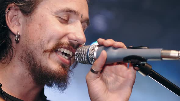 Closeup of Male Singer Singing in Microphone on Smoky Stage