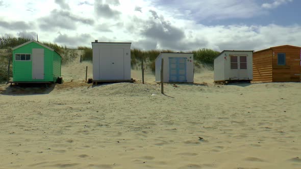 Several beach houses with different colors and shapes side by side on the beach of Texel.