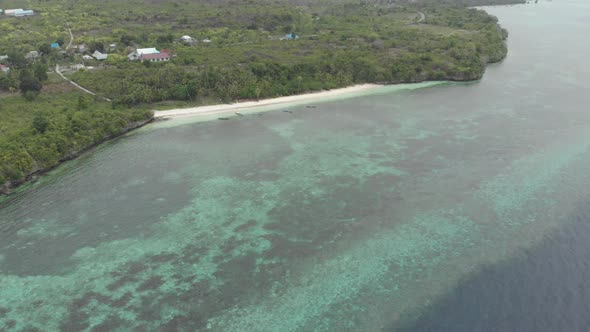 Aerial: Flying over tropical beach turquoise water coral reef , Indonesia