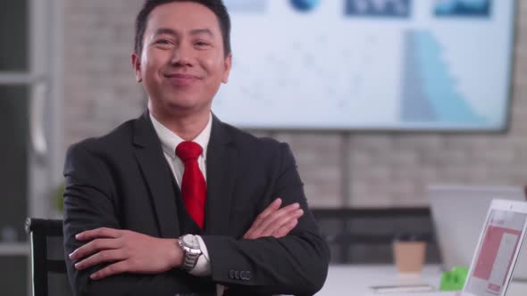 Confident young businessman sitting smiling at the camera in a meeting room.