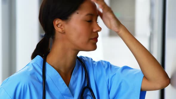 Tensed female doctor standing in corridor